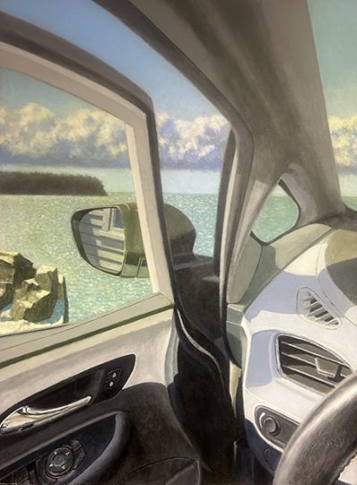 View from inside a car looking out an open door at a rocky shoreline and the sea.